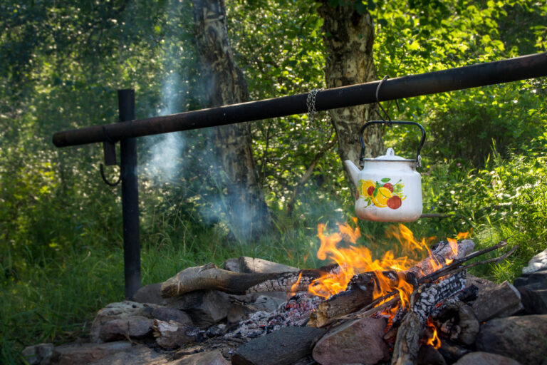 White tea kettle over campfire