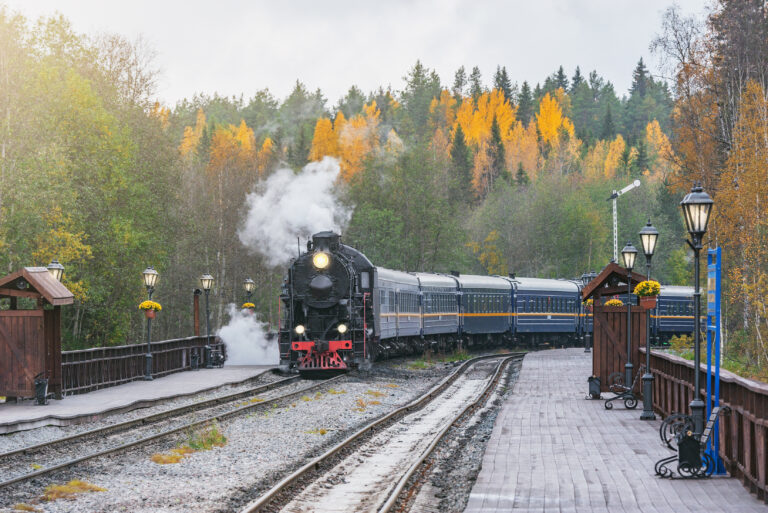 Retro steam train arrives to the station wooden platform. Ruskeala Mountain Park. Republic of Karelia